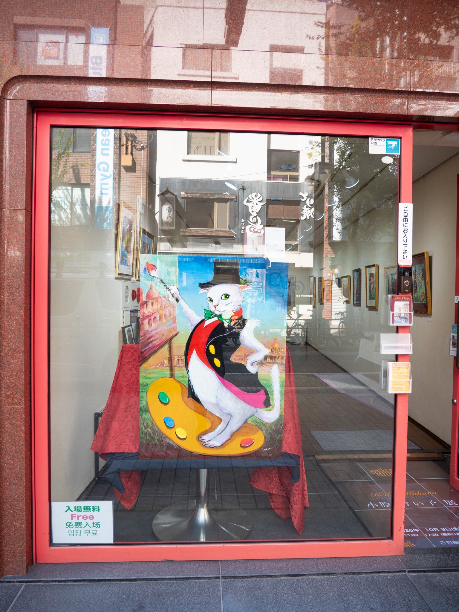 ギャラリーミウラの赤い入口と、窓辺に展示された猫の作品